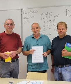Drei Männer halten Schulbücher und präsentieren ein Zeugnis