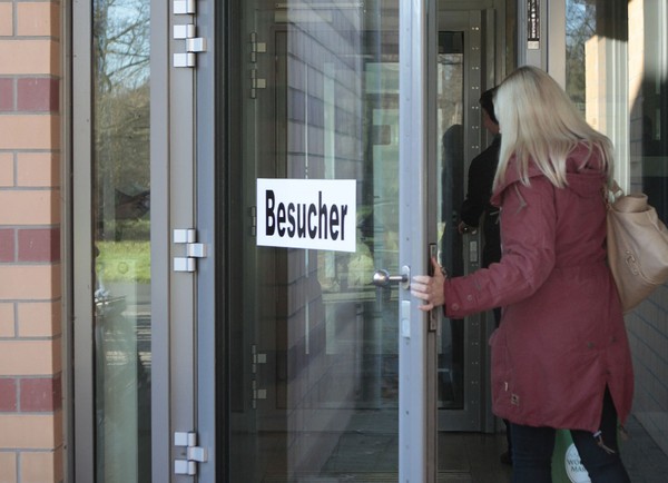 Ein Gruppe von Menschen geht innen an dem hohen Plexiglaszaun vorbei. (Bild: LWL/SchuFi)