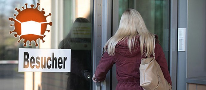 Eine Frau steht vor dem Besuchereingang. Auf das Foto ist ein Coronavirus mit Mundschutz montiert. (Bild: LWL-SchuFi)
