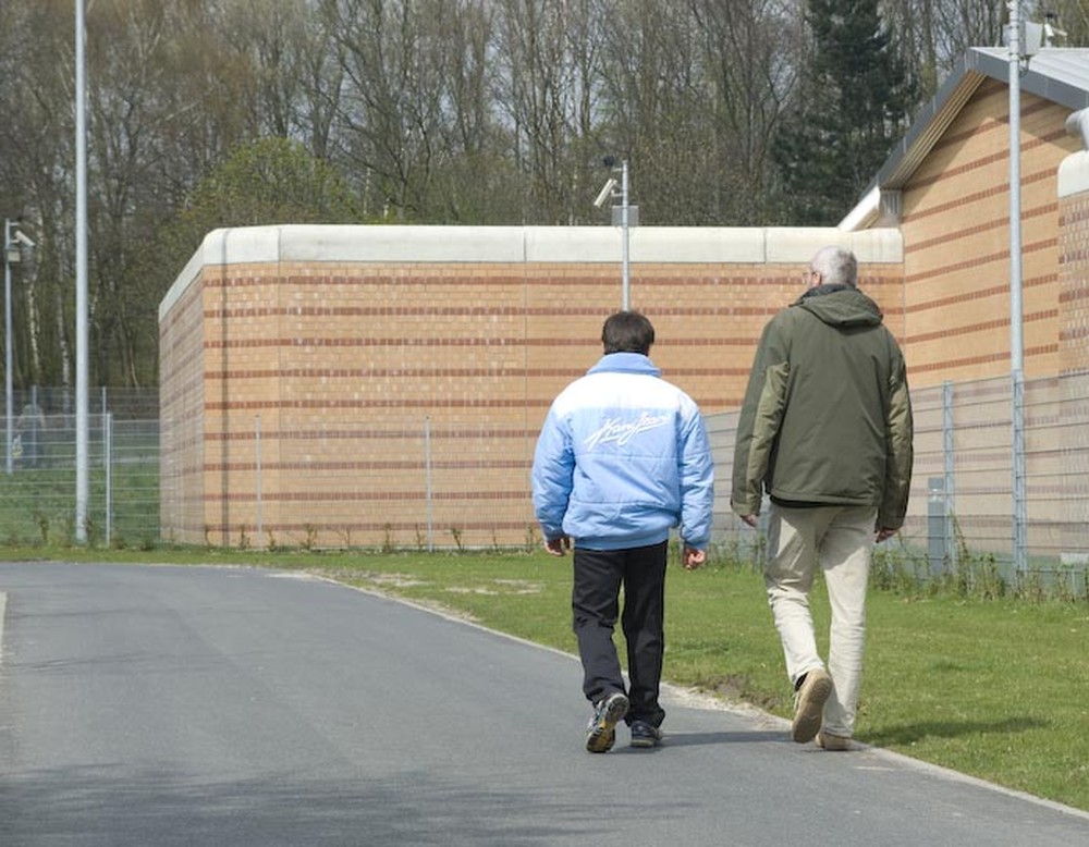 Zwei Männer laufen auf einem Fußweg an der Klinikmauer entlang. (Bild: LWL/Arendt)
