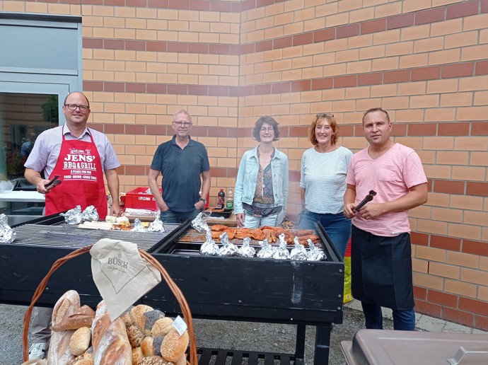 Drei Männer und zwei Frauen stehen mit Grillzangen hinter einem großen Grill. (Bild: LWL)